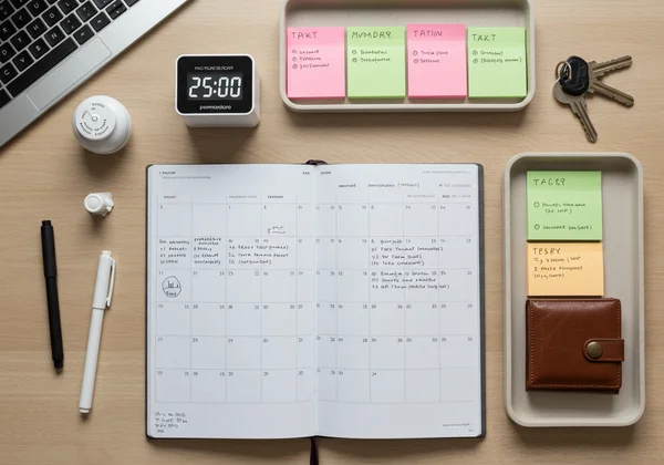 Organized desk with a planner, timer, and sticky notes.
